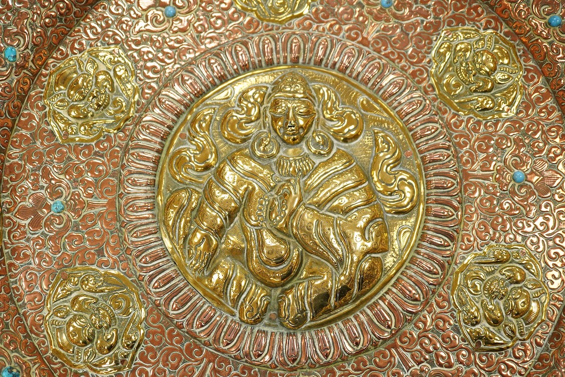 A large Nepalese brass and copper embossed tray, first half 20th century, set with simulated turquoise cabochons, 68cm diameter